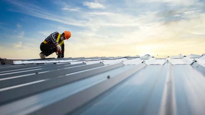 Commercial roofer inspecting a metal roof during sunset in Manhattan, NY.