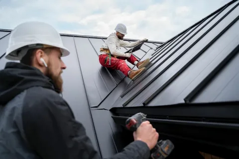 Roofers installing black metal roof